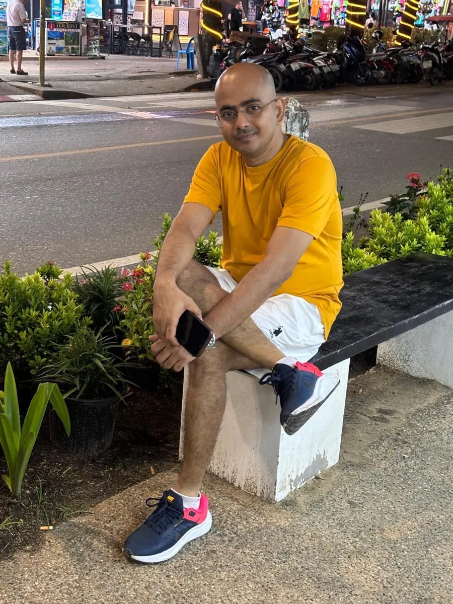 Jewel Chanda sitting by a street in a yellow t-shirt